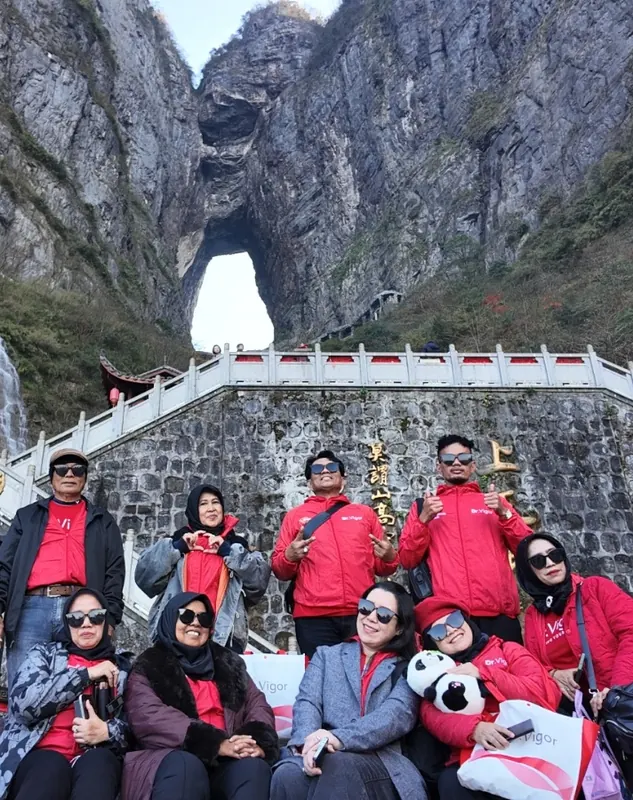 Rombongan berfoto di tangga dengan latar tebing batu