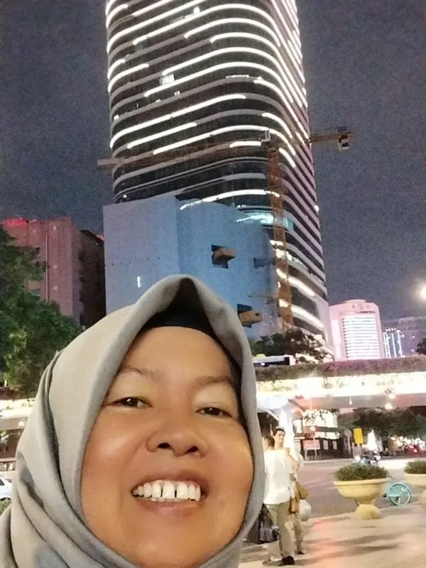 Swafoto Dr. Sofiawati dengan latar gedung tinggi di malam hari