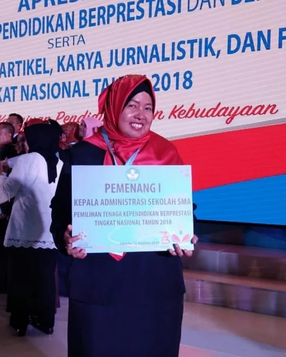 Dr. Sofiawati memegang papan Pemenang I Kepala Administrasi Sekolah SMA tingkat nasional tahun 2018