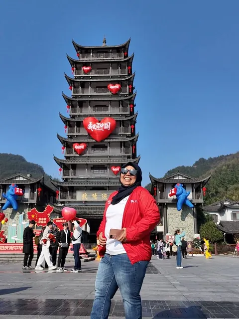Dr. Sofiawati berjaket merah berdiri di depan sebuah pagoda